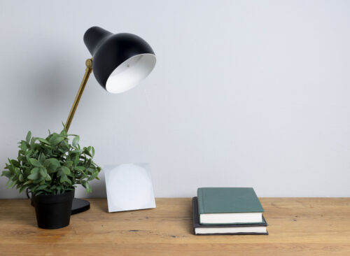 Ausgeschaltete Lampe mit zwei Büchern und digitaler Uhr auf Holzunterlage